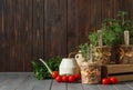 Different aromatic potted herbs, watering can and tomatoes on grey wooden table. Space for text Royalty Free Stock Photo