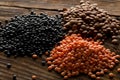 Different assorted lentils mix with red, brown and black beluga lentils on brown wooden table background