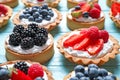 Different berry tarts on blue wooden table. Delicious pastries