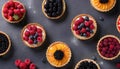 Different berry tarts on grey table, flat lay. Delicious pastries