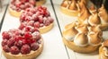 Different berry tarts and lemon meringue tart with curd on the table. Tasty passion fruit and lemon tartlet