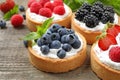 Different berry tarts on wooden table, closeup.