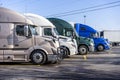 Different big rig semi trucks standing in row on truck stop ready to go