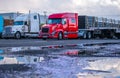 Different big rigs semi trucks with commercial cargo on semi trailers standing on the parking lot in row Royalty Free Stock Photo