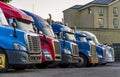 Different big rigs semi trucks standing in row on truck stop for rest at night time Royalty Free Stock Photo