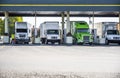 Different big rigs semi trucks with semi trailers standing on the fuel station for refueling for continue the cargo delivery route Royalty Free Stock Photo