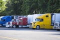 Different big rigs semi trucks with semi trailers standing in row on truck stop Royalty Free Stock Photo