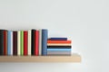 Different books on wooden shelf near white wall, space for text Royalty Free Stock Photo