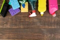 Different bottles with cleaning products and detergents and washcloths in a blue bucket on a brown wooden table. top view