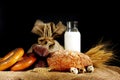 Different bread and buns on the table, next to a bag of flour, spikelets of wheat, a bottle of milk and quail eggs. Royalty Free Stock Photo