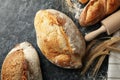 Different bread, spikelets and rolling pin on black smokey background