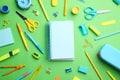 Different bright school stationery and blank notebook on light green background. Space for text