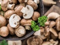 Different brown colored edible mushrooms on wooden table with herbs. Top view