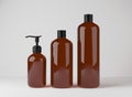 Different brown glass bottles for hair and body care products 3D render, set of cosmetic containers on gray studio Royalty Free Stock Photo