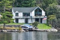 Different buildings in a grassy area on the coast of a lake during daytime, and surrounded by trees. United States flags, and boat