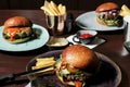 Different burgers on the table, served frenc fries and sauces