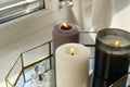 Different burning candles, perfume and vases on window sill Royalty Free Stock Photo