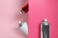 Different cans of spray paints on pink background Royalty Free Stock Photo