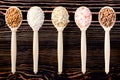 Different cereals grain in wooden spoons against wooden background. Top view of groats assortment, healthy food and eating