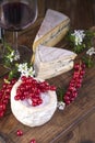 Different cheese with white and blue mold. A glass of red wine and fresh red currant berries. White flowers. Wooden background and Royalty Free Stock Photo