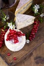 Different cheese with white and blue mold. A glass of red wine and fresh red currant berries. White flowers. Wooden background and Royalty Free Stock Photo