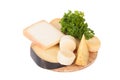 Different cheeses and a bunch of parsley lying on a board isolated on white background
