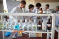 Different chemicals on the shelf and young students in the university laboratory. Science, chemistry, lab, people