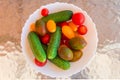 Different cherry tomatoes and cucumbers in bowl on glass table Royalty Free Stock Photo