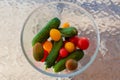 Different cherry tomatoes and cucumbers in bowl on glass table Royalty Free Stock Photo