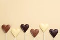 Different chocolate heart shaped lollipops on beige background, flat lay. Space for text Royalty Free Stock Photo