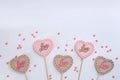 Different chocolate heart shaped lollipops and sprinkles on white background, flat lay. Space for text Royalty Free Stock Photo