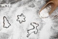 Different Christmas cookie shapes made of flour near scoop, flat lay