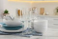 Different clean dishware, cutlery and glasses on white table in kitchen Royalty Free Stock Photo