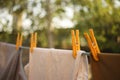 Different clothes are dried on a rope with yellow clothespins in a summer garden. Close up, blurred natural background Royalty Free Stock Photo