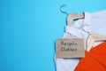 Different clothes with recycling label and hangers on light blue background, flat lay. Space for text Royalty Free Stock Photo