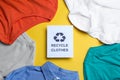 Different clothes with recycling label on yellow background, flat lay Royalty Free Stock Photo