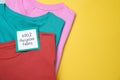 Different clothes with recycling label on yellow background, top view. Space for text Royalty Free Stock Photo