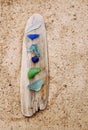 Blue, green, white sea glass or beach glass on driftwood in beach.