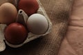 different colored chicken eggs in a box on a burlap