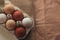 different colored chicken eggs in a box on a burlap background