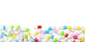 Different colored pill capsules border edge over white background, medical treatment, pharmaceutical or medication concept