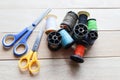 Different colored spools thread with needles, and scissors isolated on wooden background closeup. Royalty Free Stock Photo