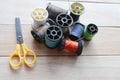 Different colored spools thread with needles, and scissors isolated on wooden background closeup. Royalty Free Stock Photo