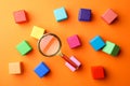 Different colorful cubes and magnifier glass on orange background. Find keywords concept