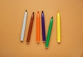 Different colorful markers on light brown background, flat lay