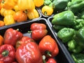 Different colors of capsicums for sale in a vegetable market for business and kept in a tray for Orange green and Red colors