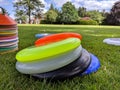 Different coloured ultimate frisbees piled up on the grass