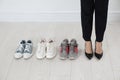 Different comfortable sneakers near businesswoman wearing high heel shoes indoors, closeup Royalty Free Stock Photo