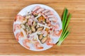Different cooked seafoods on white dish, green onion, top view