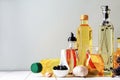 Different cooking oils and ingredients on white wooden table against grey background, space for text Royalty Free Stock Photo